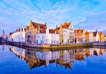 Cityscape view of Bruges and traditional houses reflected in water at sunrise in Belgium