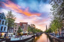 The most famous canals and embankments of Amsterdam city during sunset General view of the cityscape and traditional Netherlands architecture