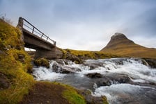 Cold water in Iceland Waterfall in rocky mountains Fresh and green grass Beautiful mountain range in the backgrond