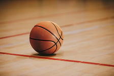 Classic Basketball on Wooden Court Floor Close Up with Blurred Arena in Background Orange Ball on a Hardwood Basketball Court