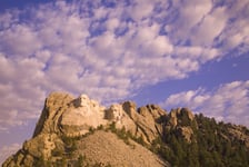 White puffy clouds behind Presidents George Washington Thomas Jefferson Teddy Roosevelt and Abraham Lincoln at Mount Rushmore National Memorial South Dakota